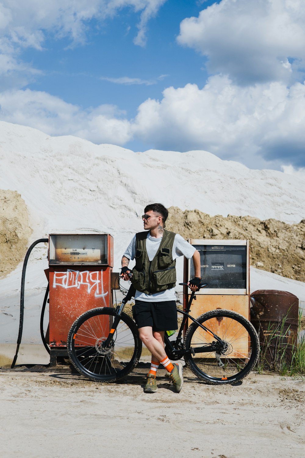 um homem ao lado de uma bicicleta ao lado de uma bomba de gasolina