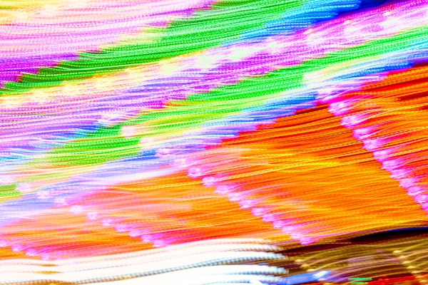 A vibrant, abstract display of colorful light streaks with a variety of bright hues including purple, green, orange, and white blending together in dynamic motion.