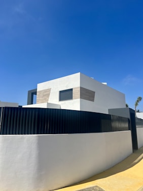 Modern minimalist home exterior with clean lines and natural landscaping at sunset.