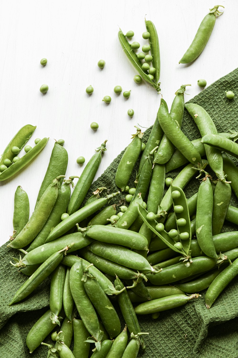 a pile of green beans sitting on top of a green towel