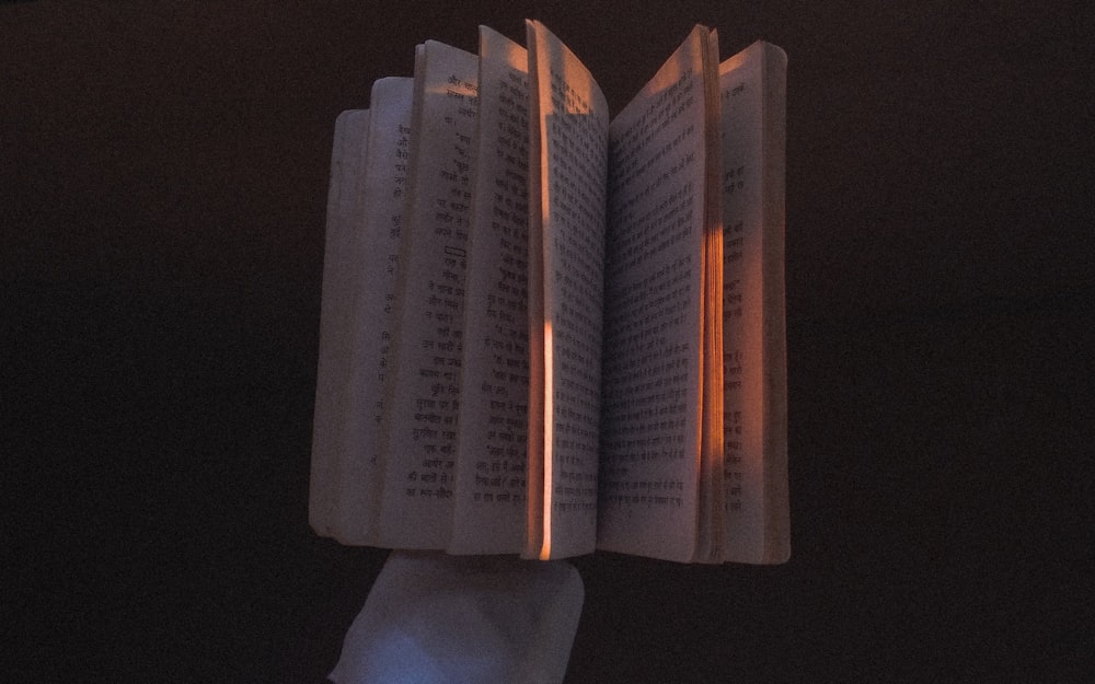 a hand holding a lit up book in the dark