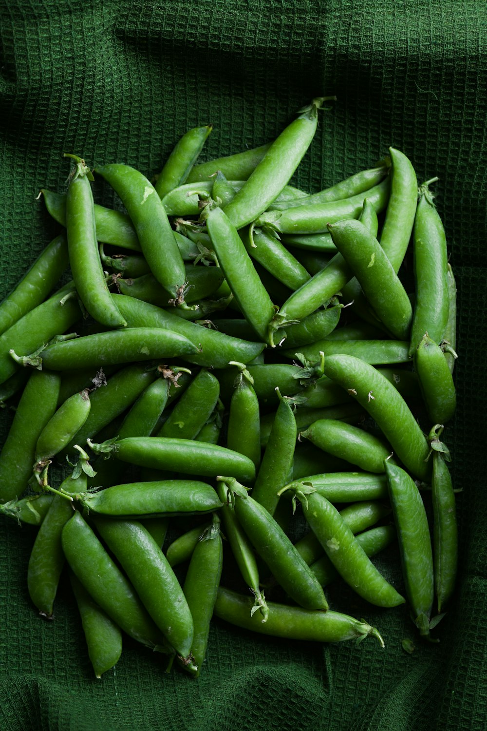 a pile of green beans sitting on top of a green cloth