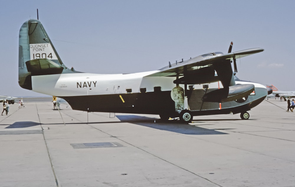 a navy plane sitting on top of an airport tarmac