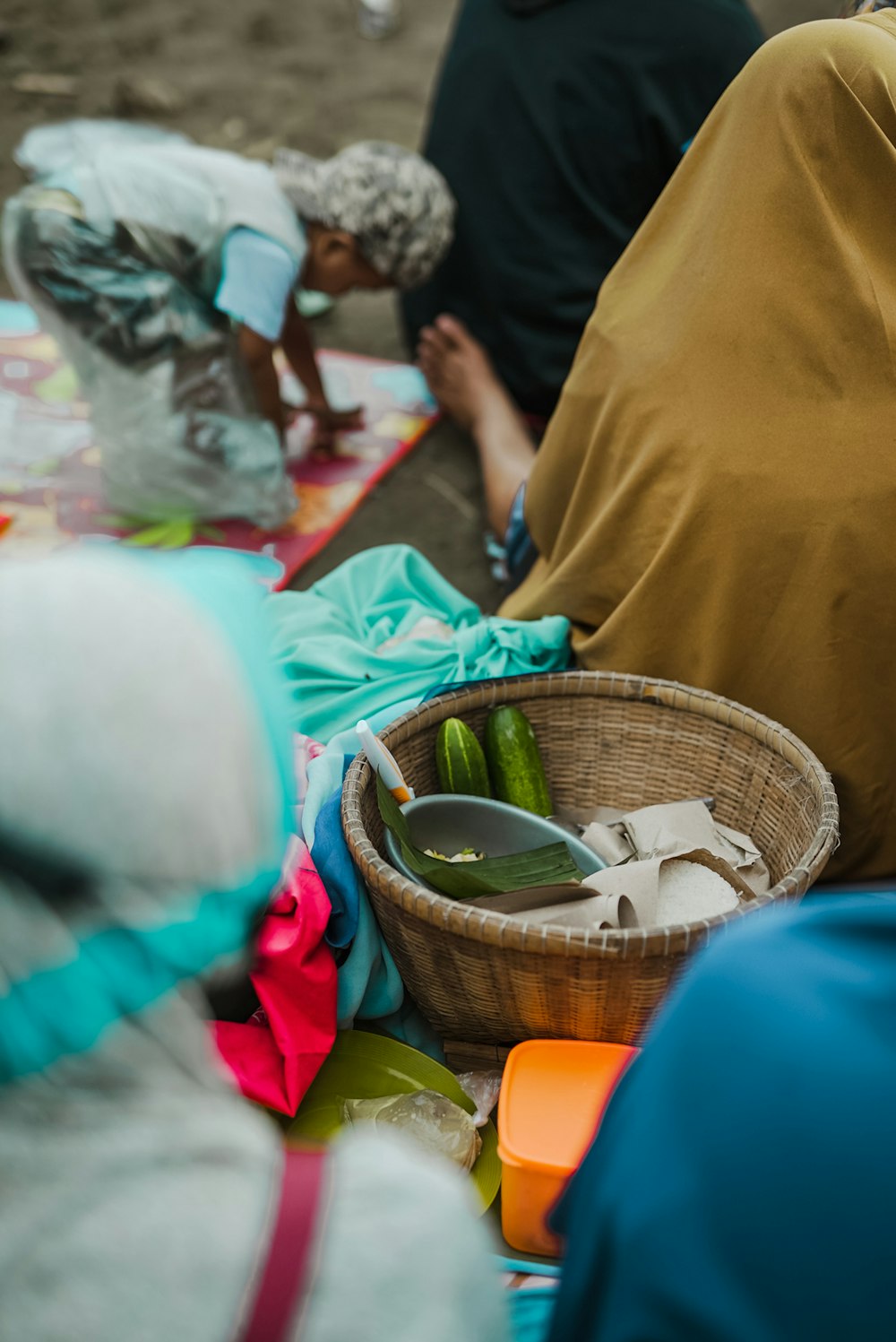 a group of people sitting around a basket of food