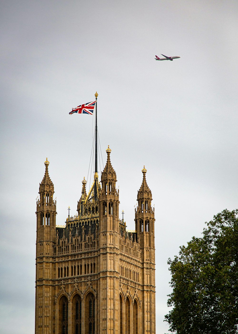 a plane flying over a large building with a flag on top
