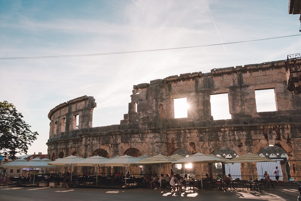 an old building with tables and umbrellas in front of it