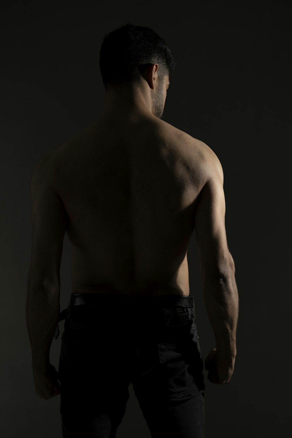 a shirtless man with no shirt standing in a dark room