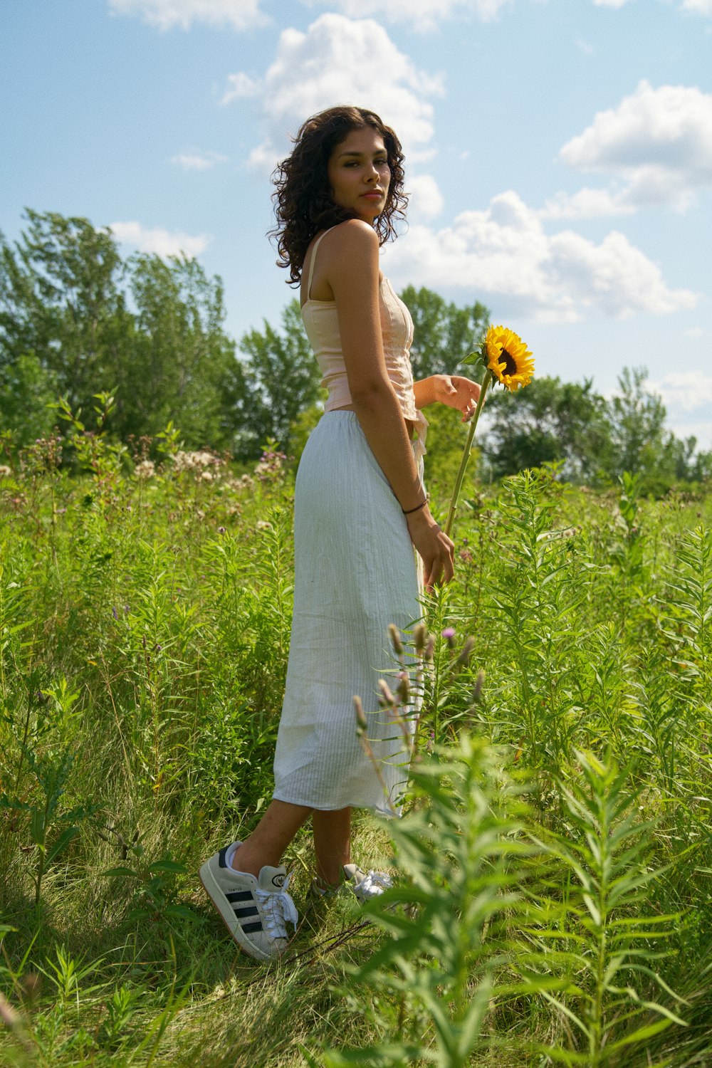 a woman standing in a field with a sunflower