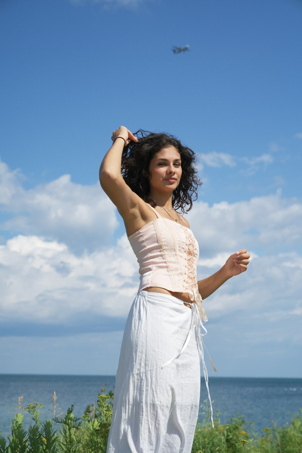 a woman in a white dress standing by the ocean