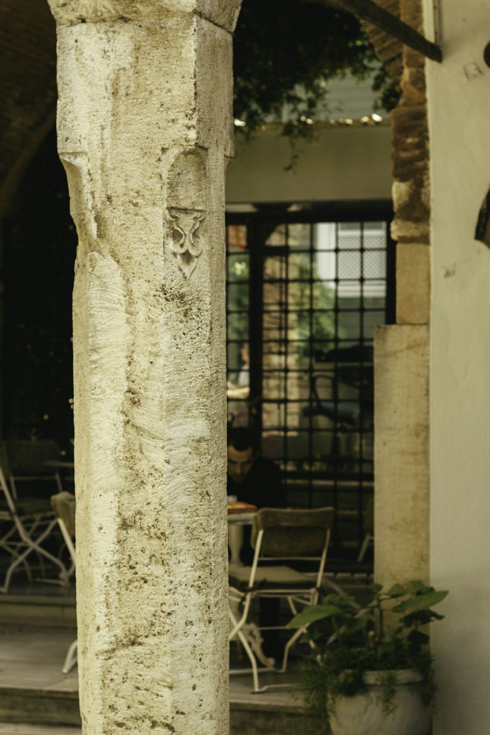 a cat sitting on a stone pillar in front of a building