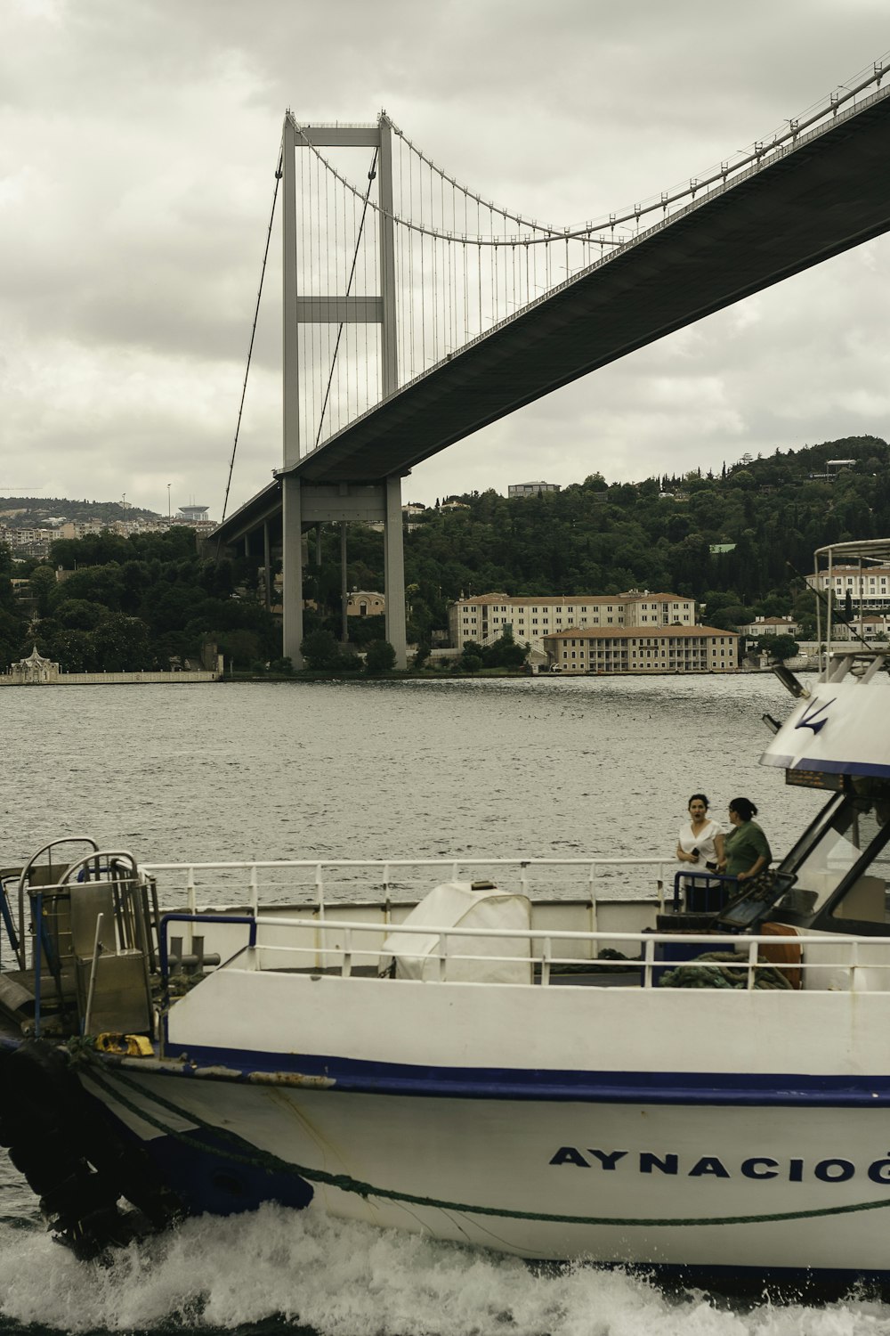 a white and blue boat traveling under a bridge