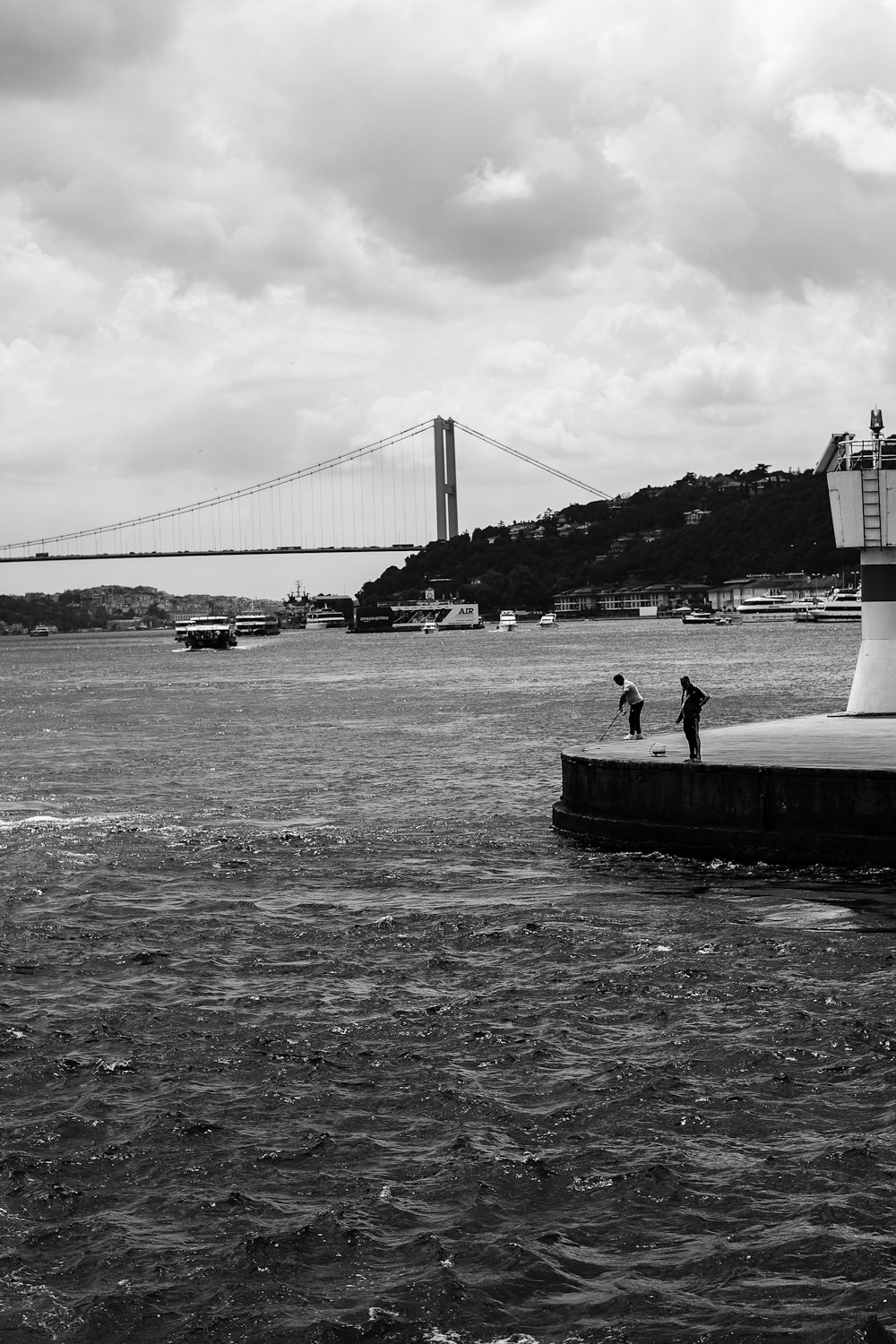 a black and white photo of a person standing on a pier