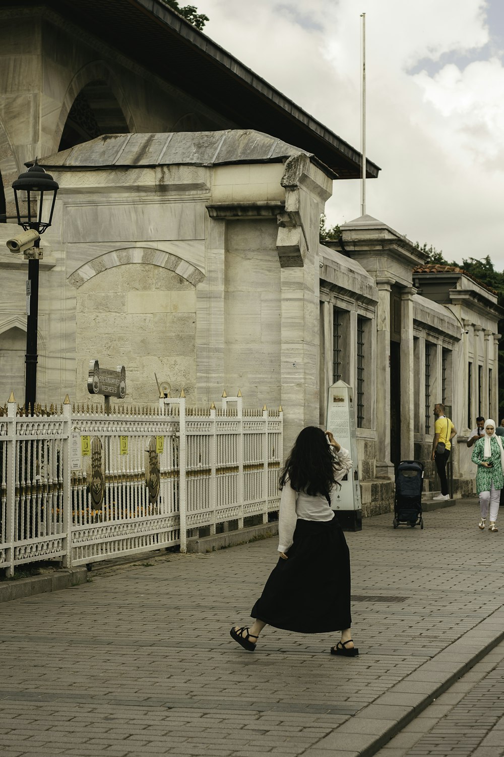 a woman in a black and white dress walking down a street