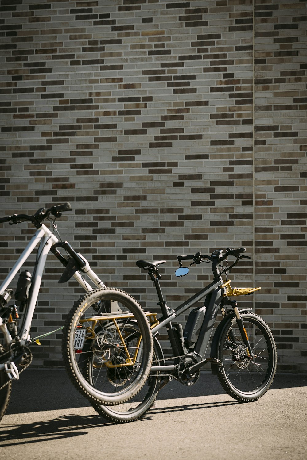 two bikes parked next to each other in front of a brick wall