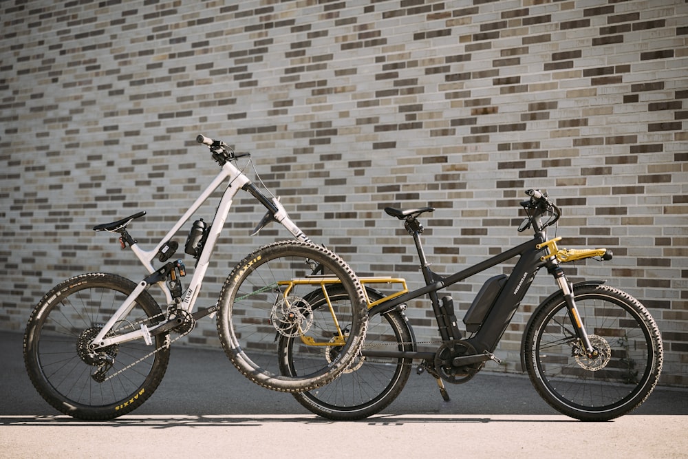 two bikes parked next to each other in front of a brick wall