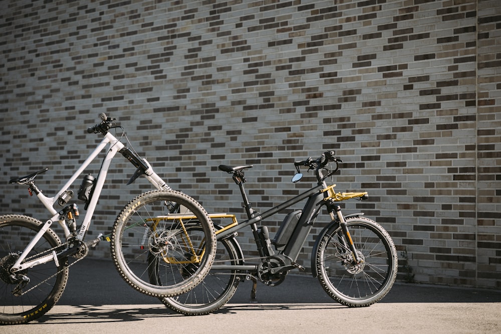 two bikes parked next to each other in front of a brick wall