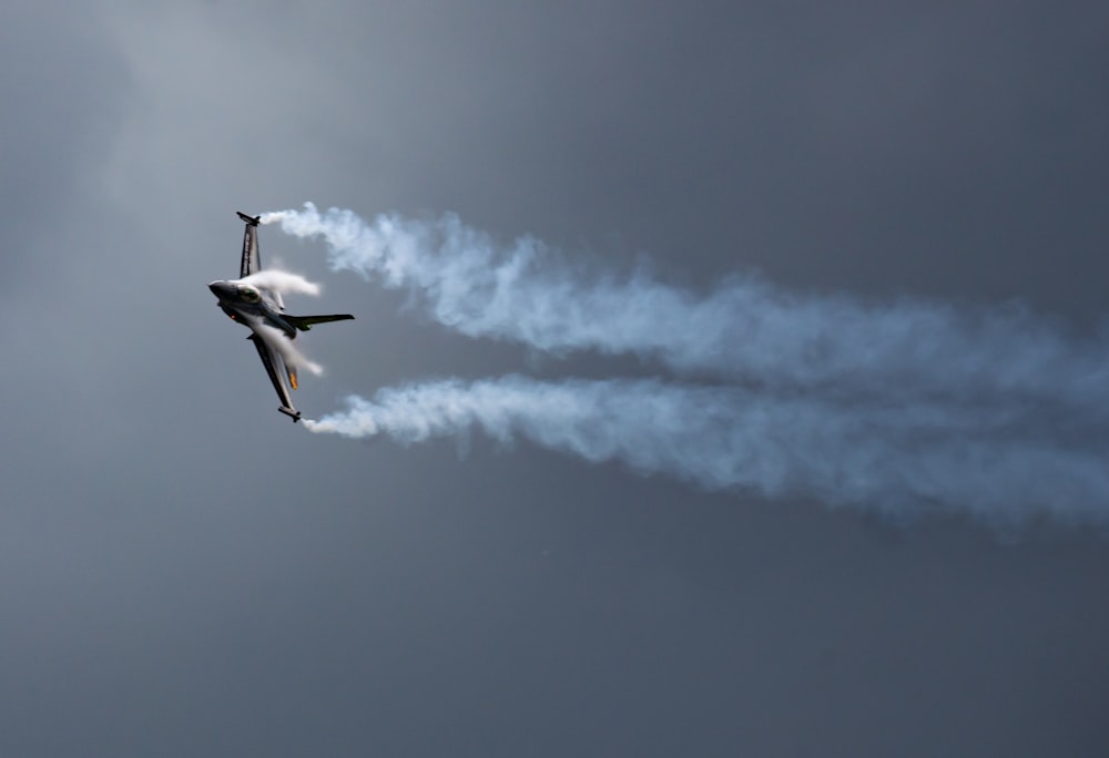 two jets flying in the sky with smoke coming out of them