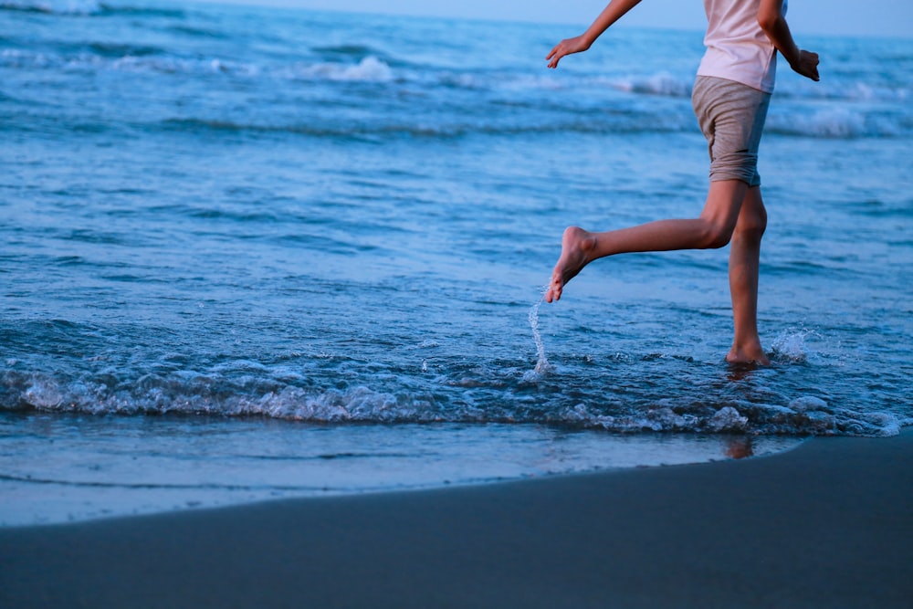 a woman is running in the water at the beach