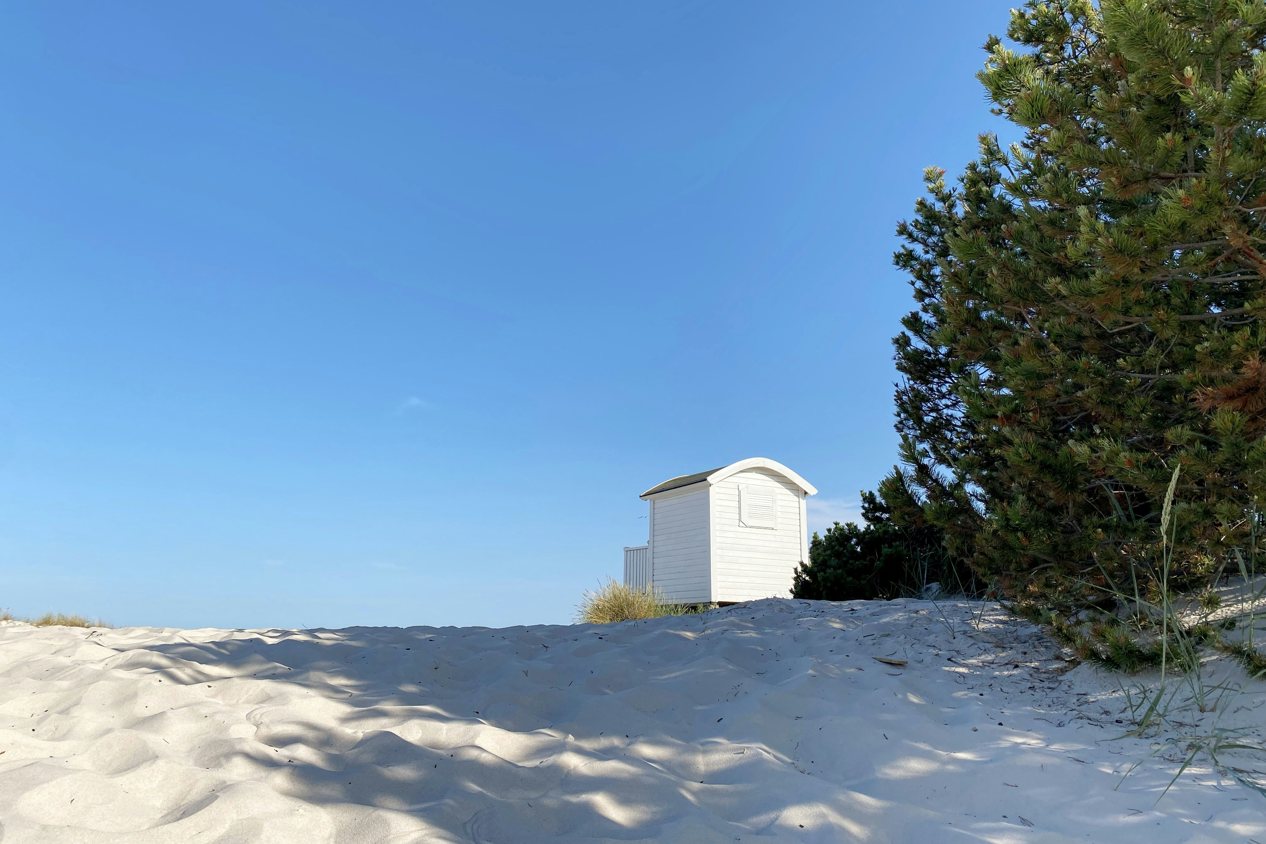 a white building sitting on top of a sandy hill