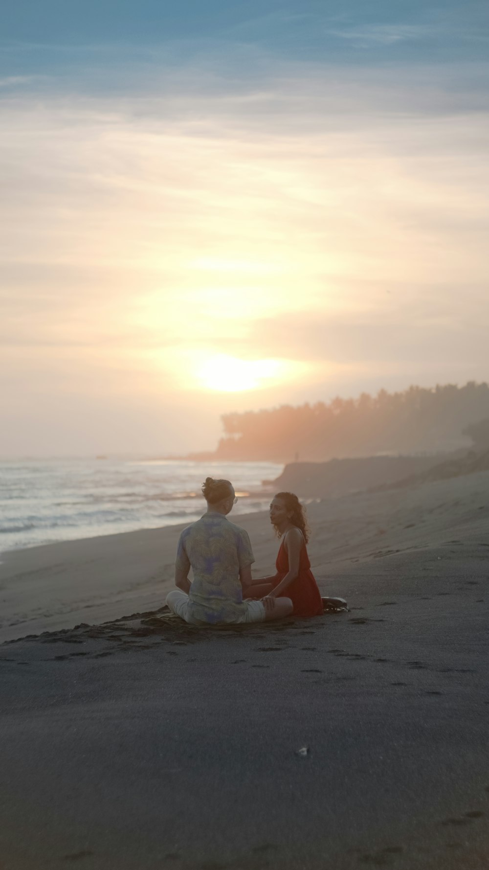 a couple of people sitting on top of a sandy beach