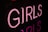 Neon pink letters spell out the word 'GIRLS' against a dark background, casting a soft glow around them.