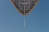 Close-up of a bungee jumper launching off a vibrant red crane against a clear blue sky.