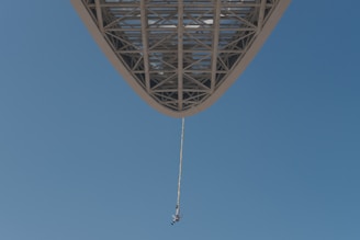 An exhilarating bungee jump with a jumper mid-air against a clear sky.