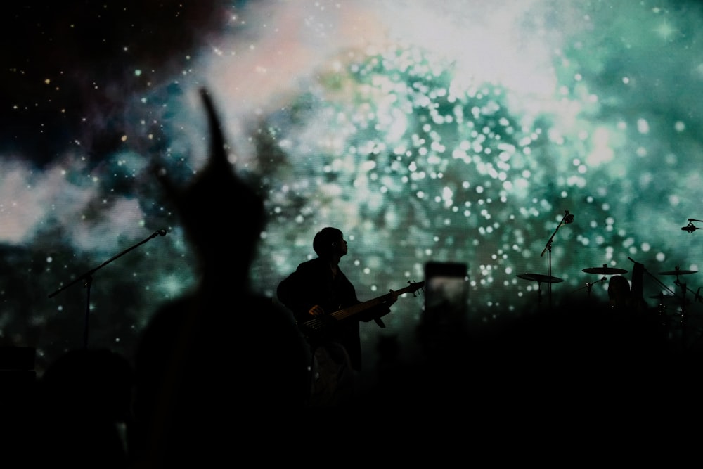 a man playing a guitar in front of fireworks