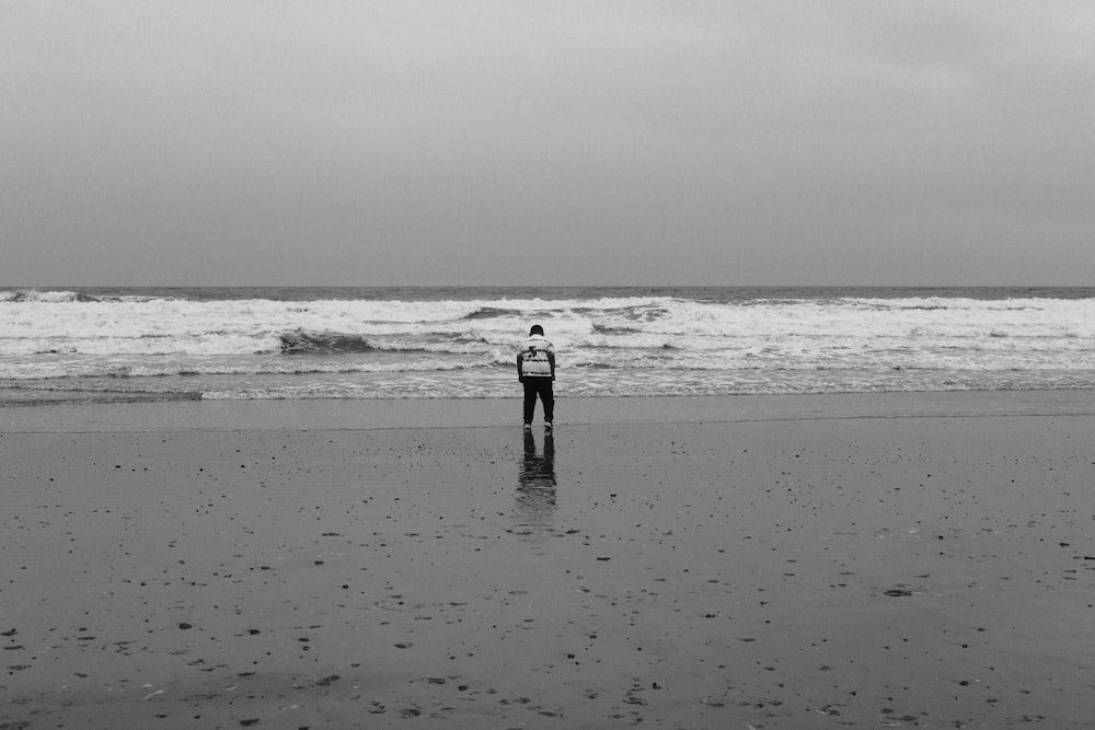 a man standing on top of a beach next to the ocean