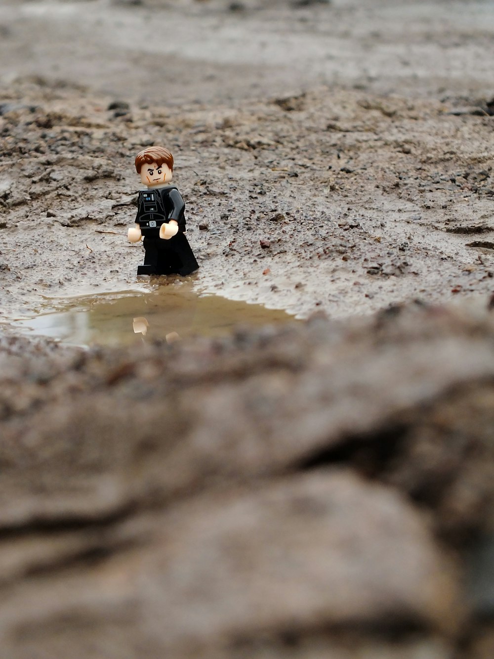 a lego man standing in a puddle of water