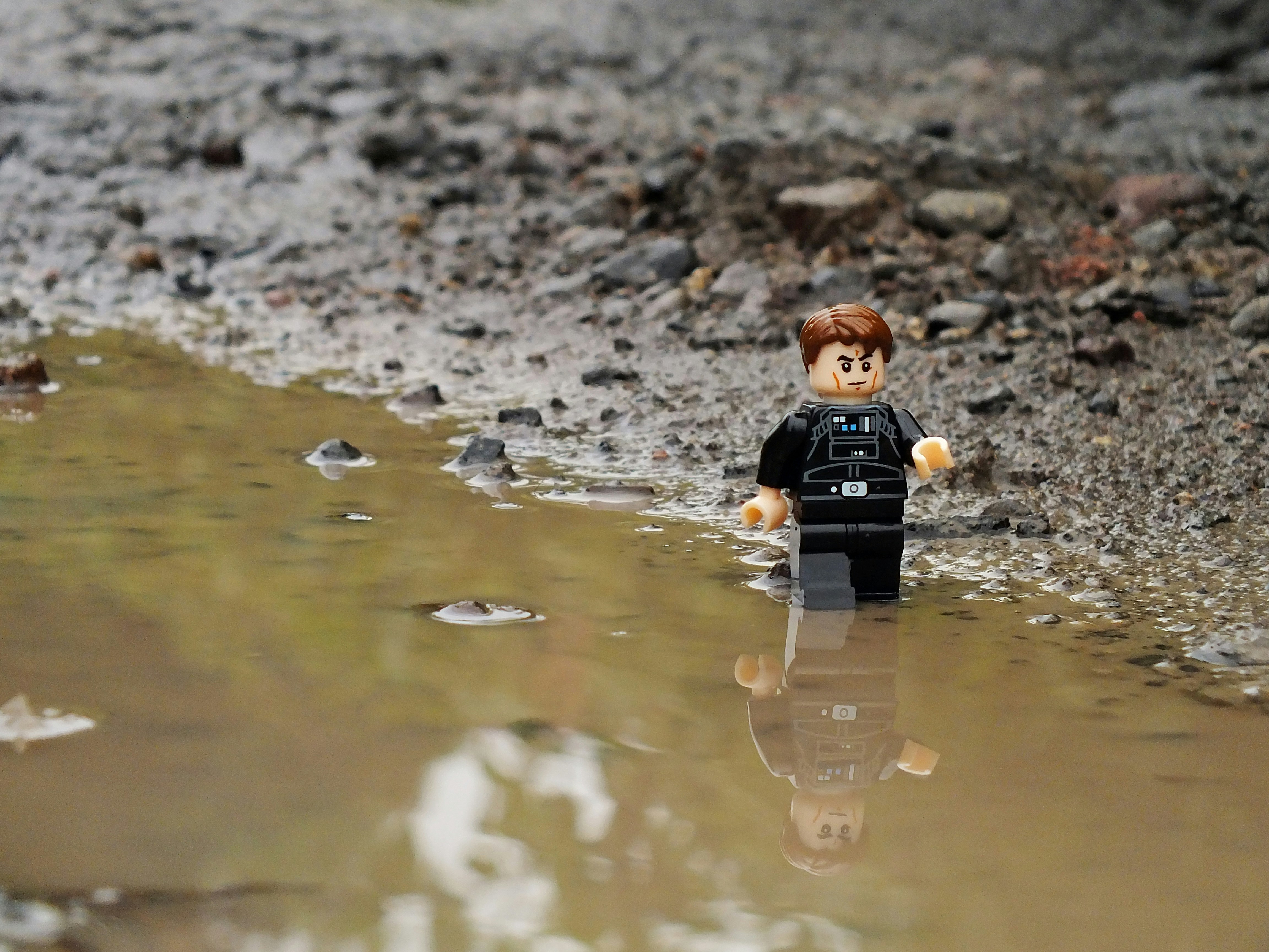 a lego man standing in a puddle of water