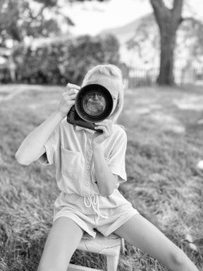 A black-and-white portrait of Tatiana Lebedianskaia adjusting her camera outdoors.