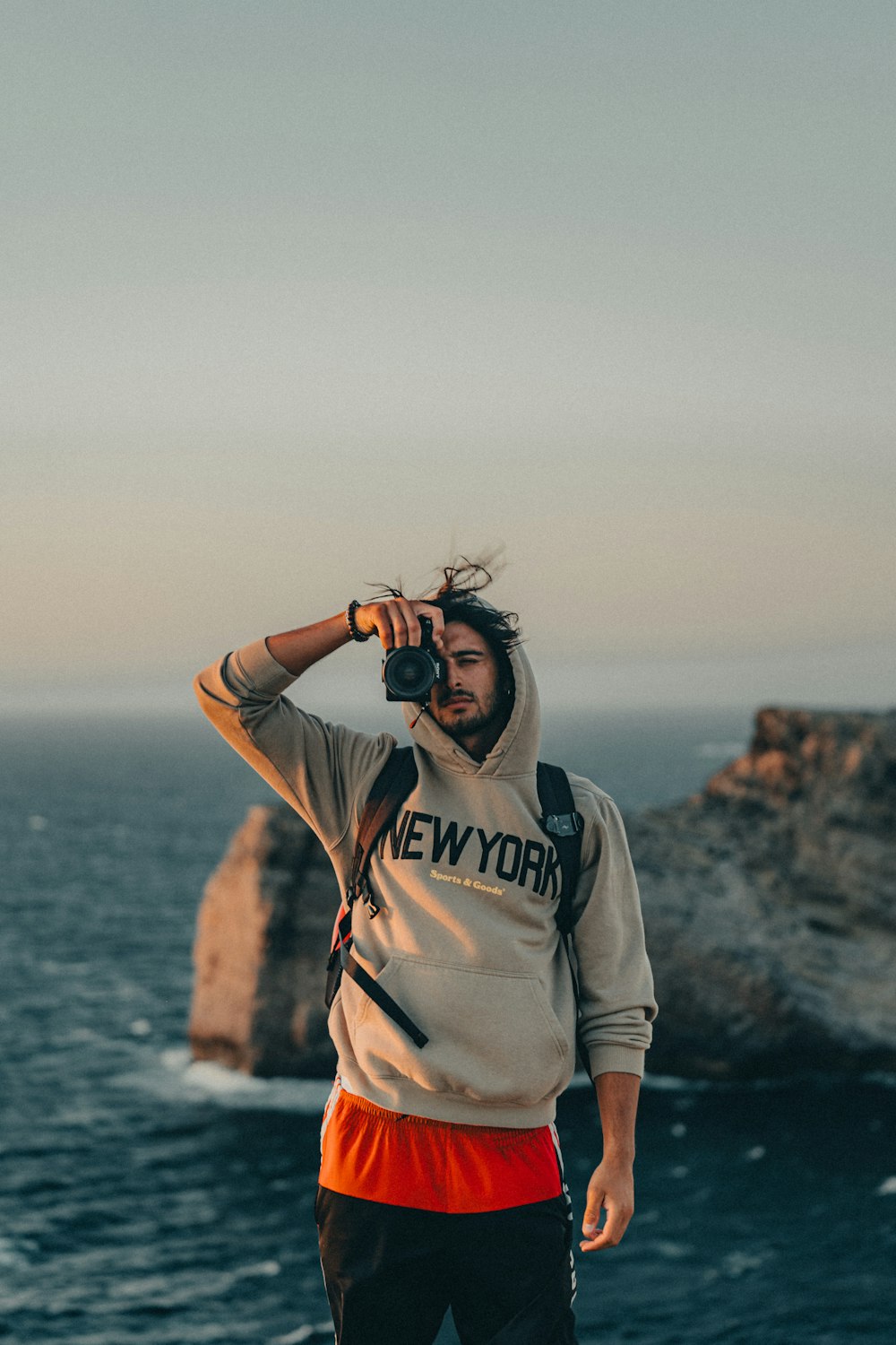 a man standing on top of a cliff next to the ocean