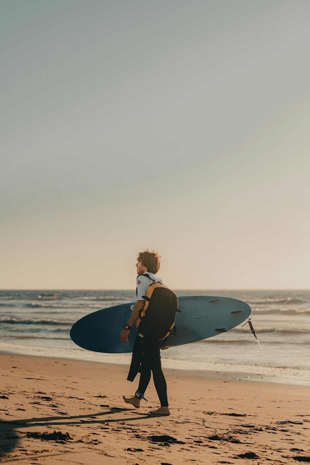 Un hombre cargando una tabla de surf a través de una playa