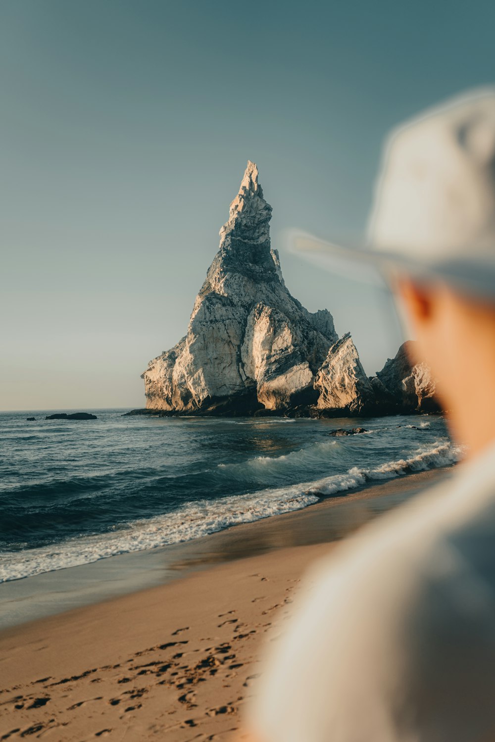 a man standing on top of a sandy beach next to the ocean