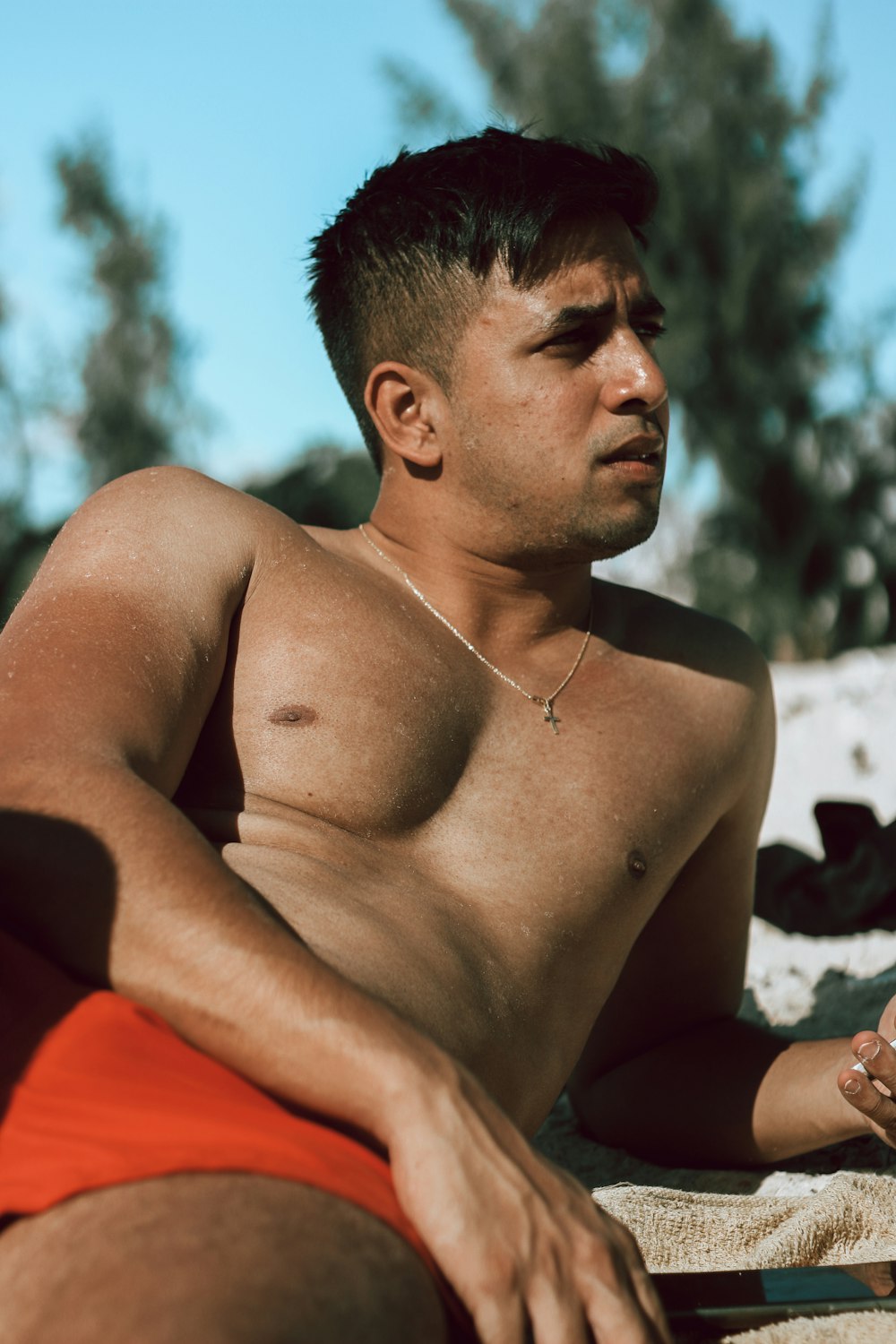 a man with no shirt sitting on a beach