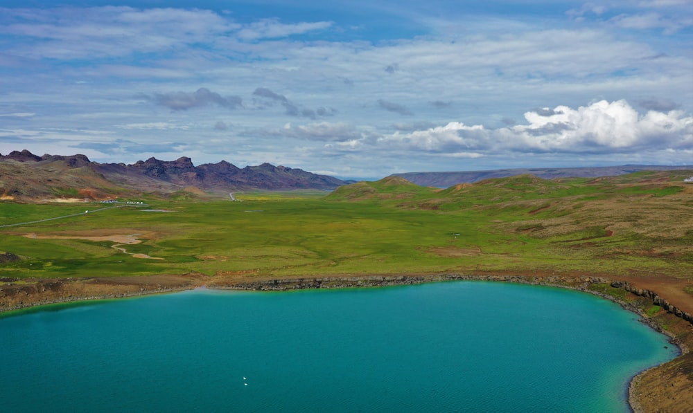 a blue lake surrounded by mountains and green grass