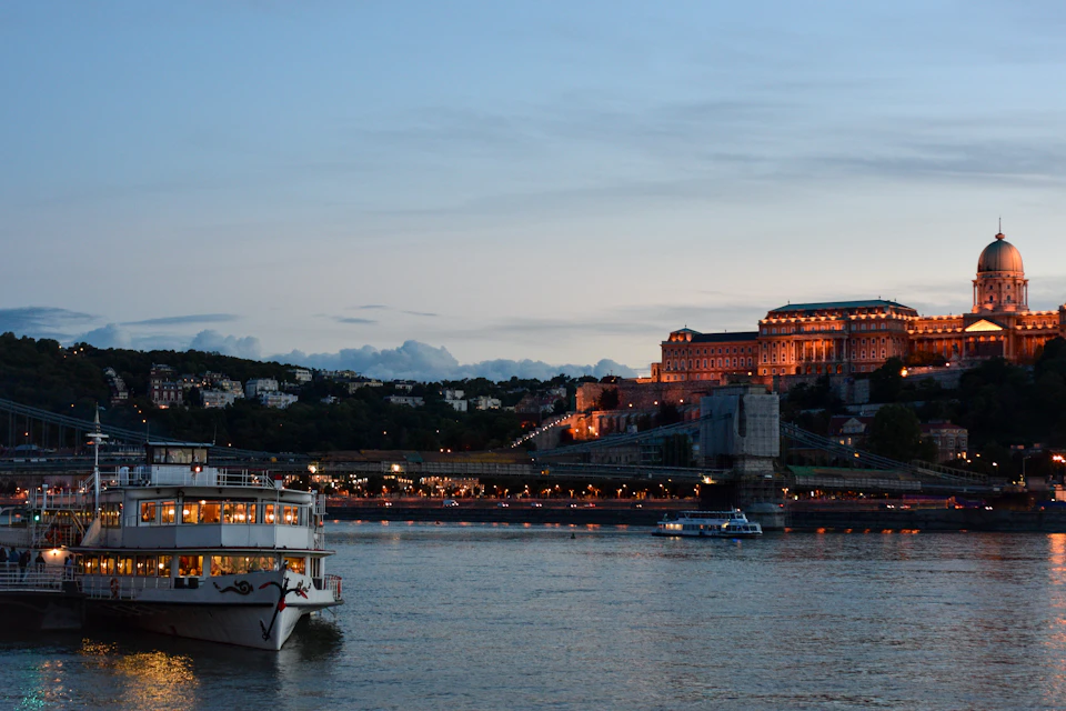 Serene night scene on Danube River in Budapest with illuminated riverbanks and castle silhouette