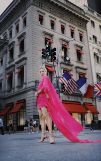 A vibrant plus size model wearing a stylish pink dress, smiling confidently in a sunlit urban setting.