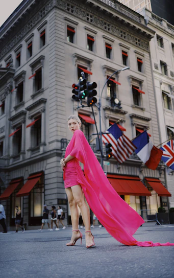 A vibrant plus size model wearing a stylish pink dress, smiling confidently in a sunlit urban setting.