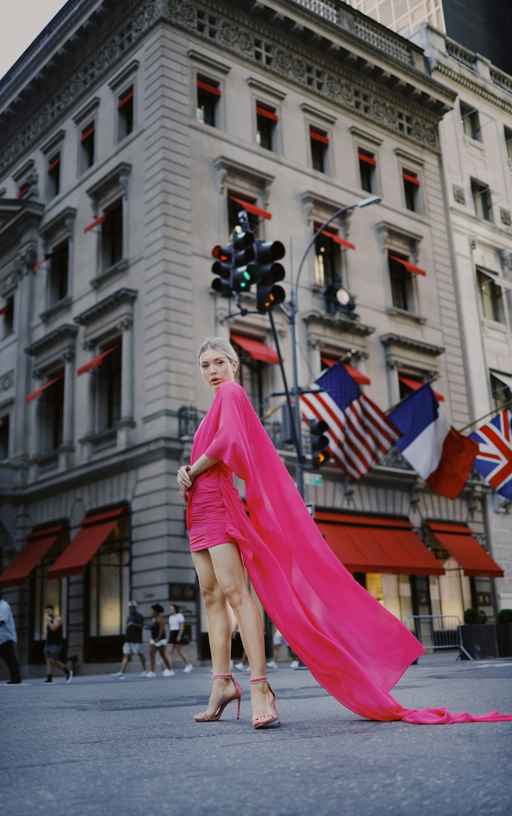 Une femme en robe rose debout devant un immeuble