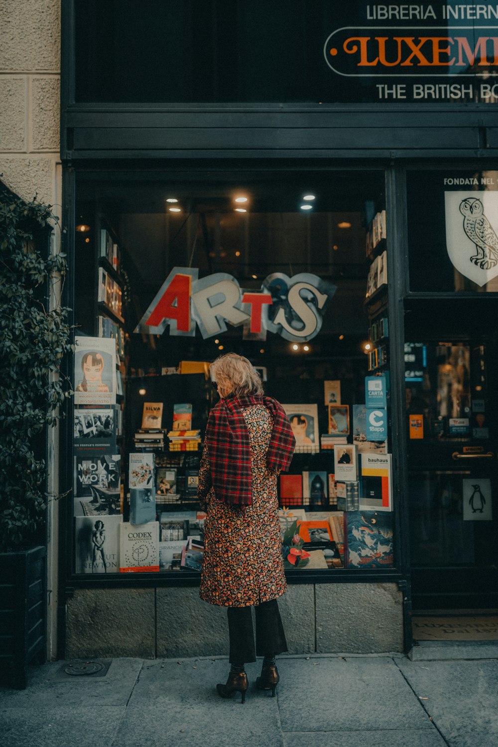 Una mujer parada frente a la ventana de una tienda