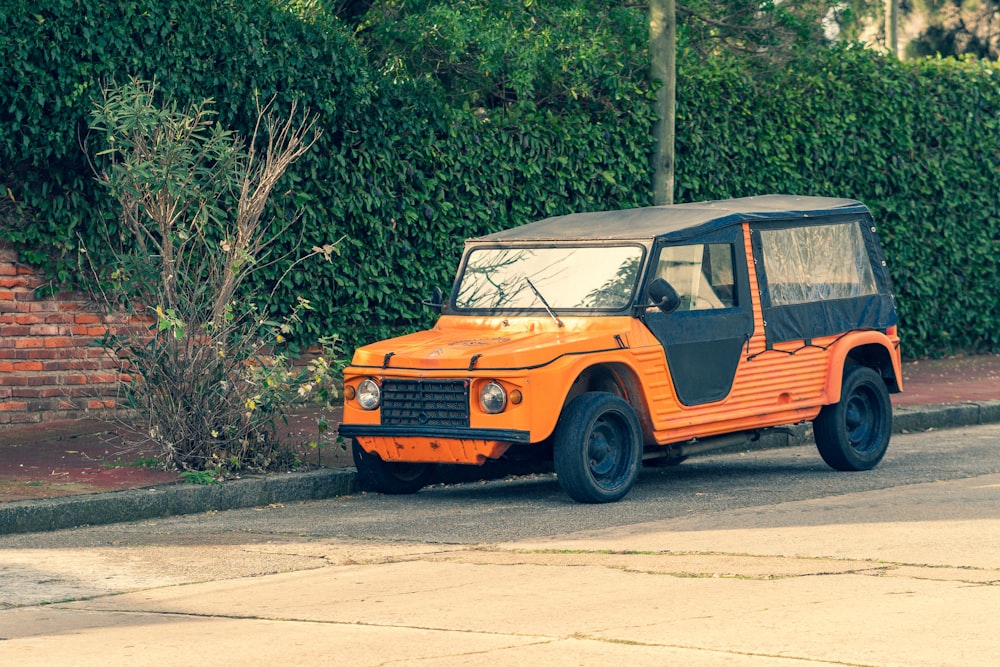 Un jeep naranja estacionado al costado de la carretera