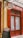 A storefront with vibrant red doors and window frames, featuring a traditional butcher shop sign that reads 'Boucherie Charcuterie' in French. A chalkboard menu is displayed outside, listing various offerings. The atmosphere suggests a quaint, classic European shop.