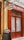 A storefront with vibrant red doors and window frames, featuring a traditional butcher shop sign that reads 'Boucherie Charcuterie' in French. A chalkboard menu is displayed outside, listing various offerings. The atmosphere suggests a quaint, classic European shop.