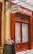 A storefront with vibrant red doors and window frames, featuring a traditional butcher shop sign that reads 'Boucherie Charcuterie' in French. A chalkboard menu is displayed outside, listing various offerings. The atmosphere suggests a quaint, classic European shop.