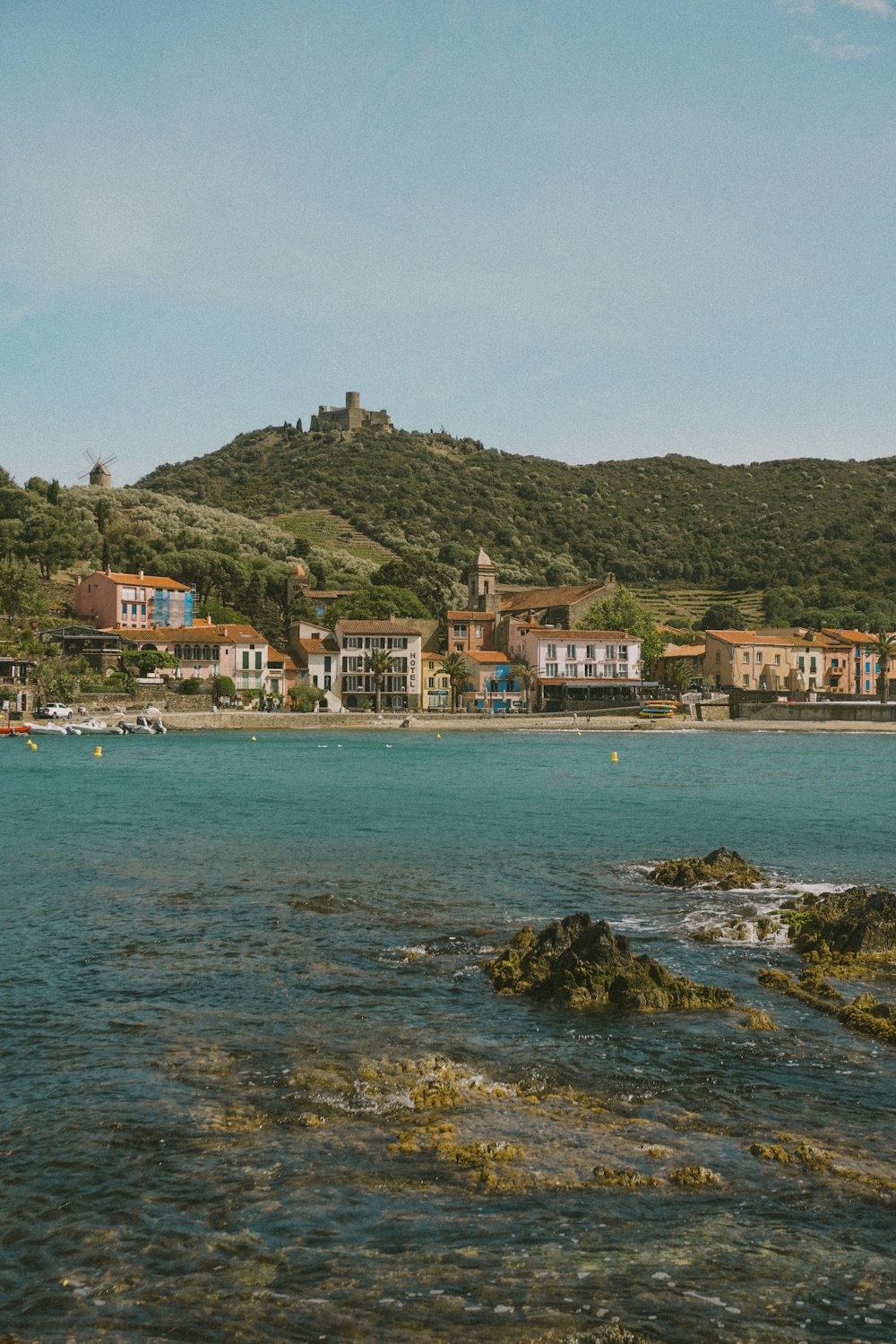 a body of water with houses on a hill in the background