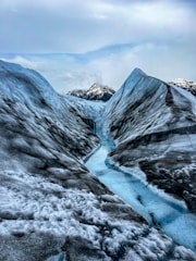 A cinematic 4k image of a deep blue glacier melting into a crystal-clear river under a twilight sky.