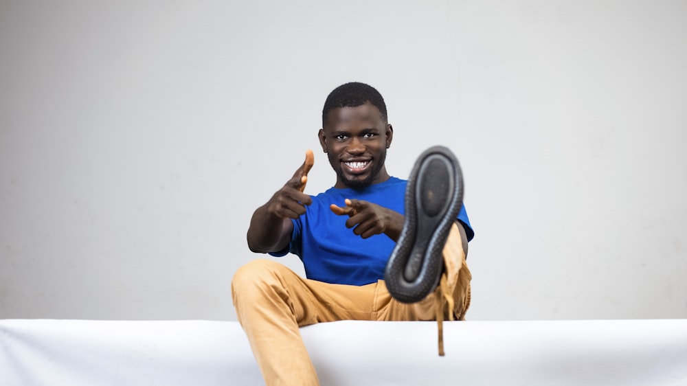 a man sitting on top of a white couch holding a shoe