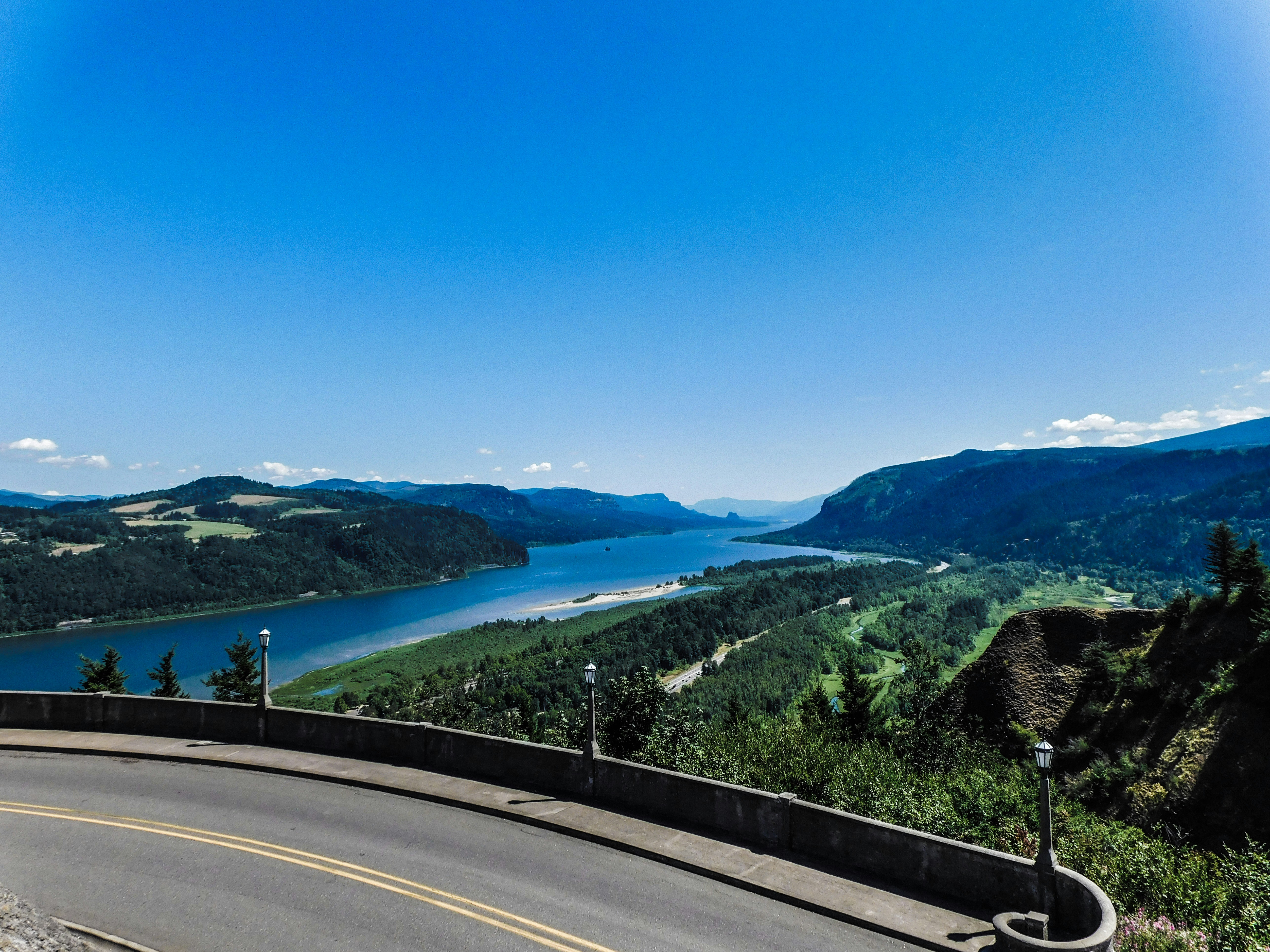 a curved road with a lake in the distance